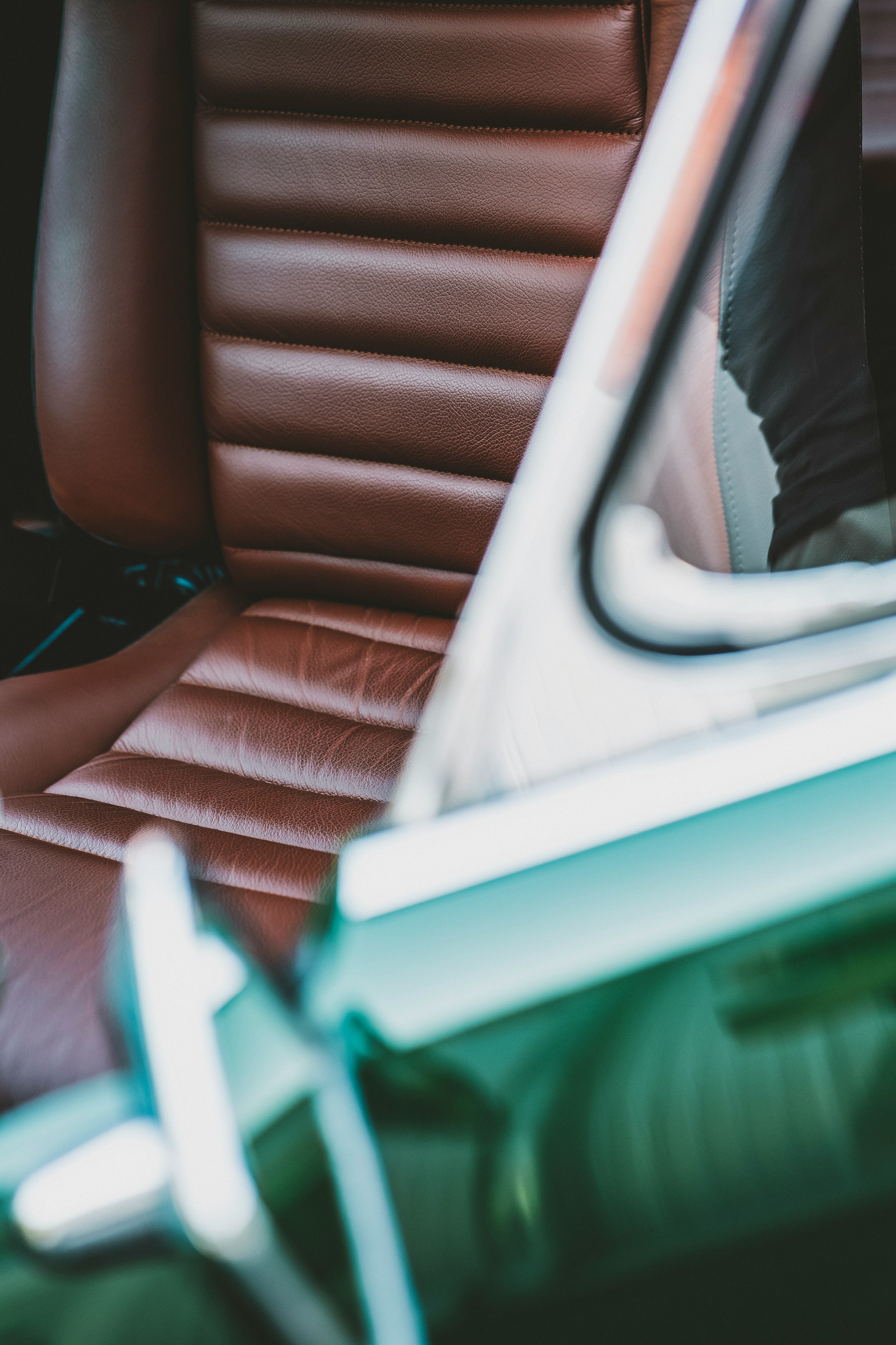 person in black pants sitting on brown leather car seat